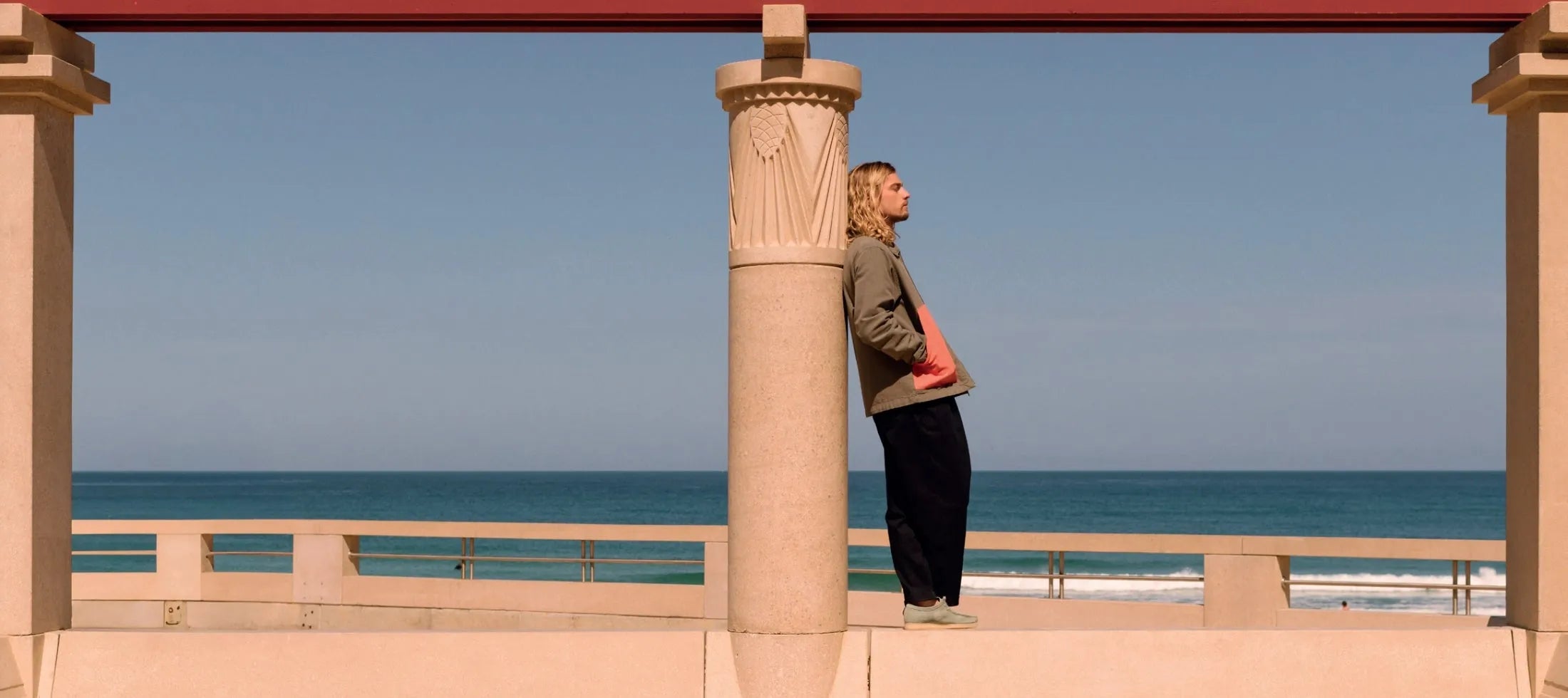 homme appuyait sur colonne habillé bask in the sun arriere plan mer