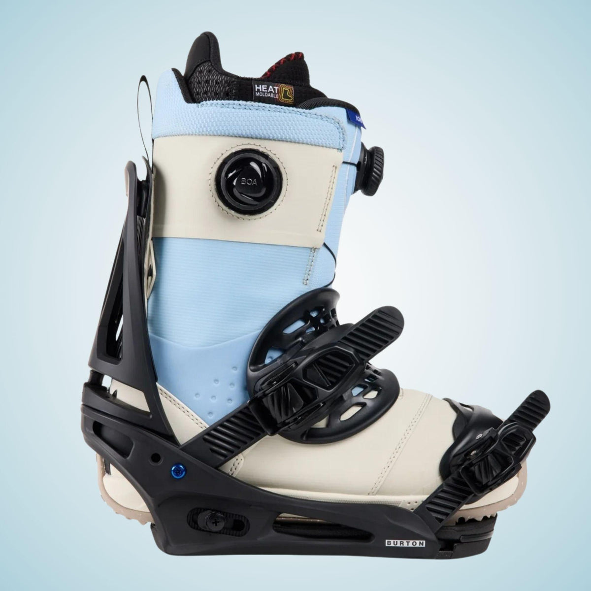 Boots grise et bleue installée dans la fixation snowboard, maintenue par les deux straps sur une embase sombre