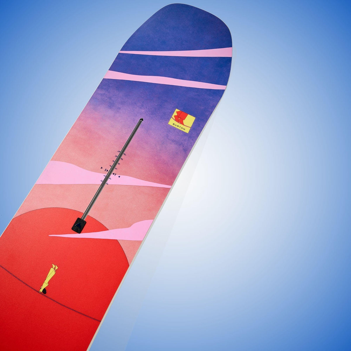Gros plan incliné sur la spatule bleue et rose, traversée de bandes diagonales et d’un petit emblème coloré
