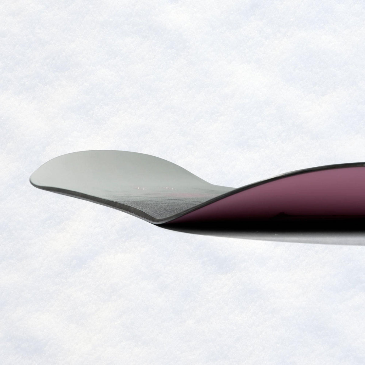 Vue latérale de la planche montrant les spatules relevées et le contraste entre semelle rose et face supérieure grise