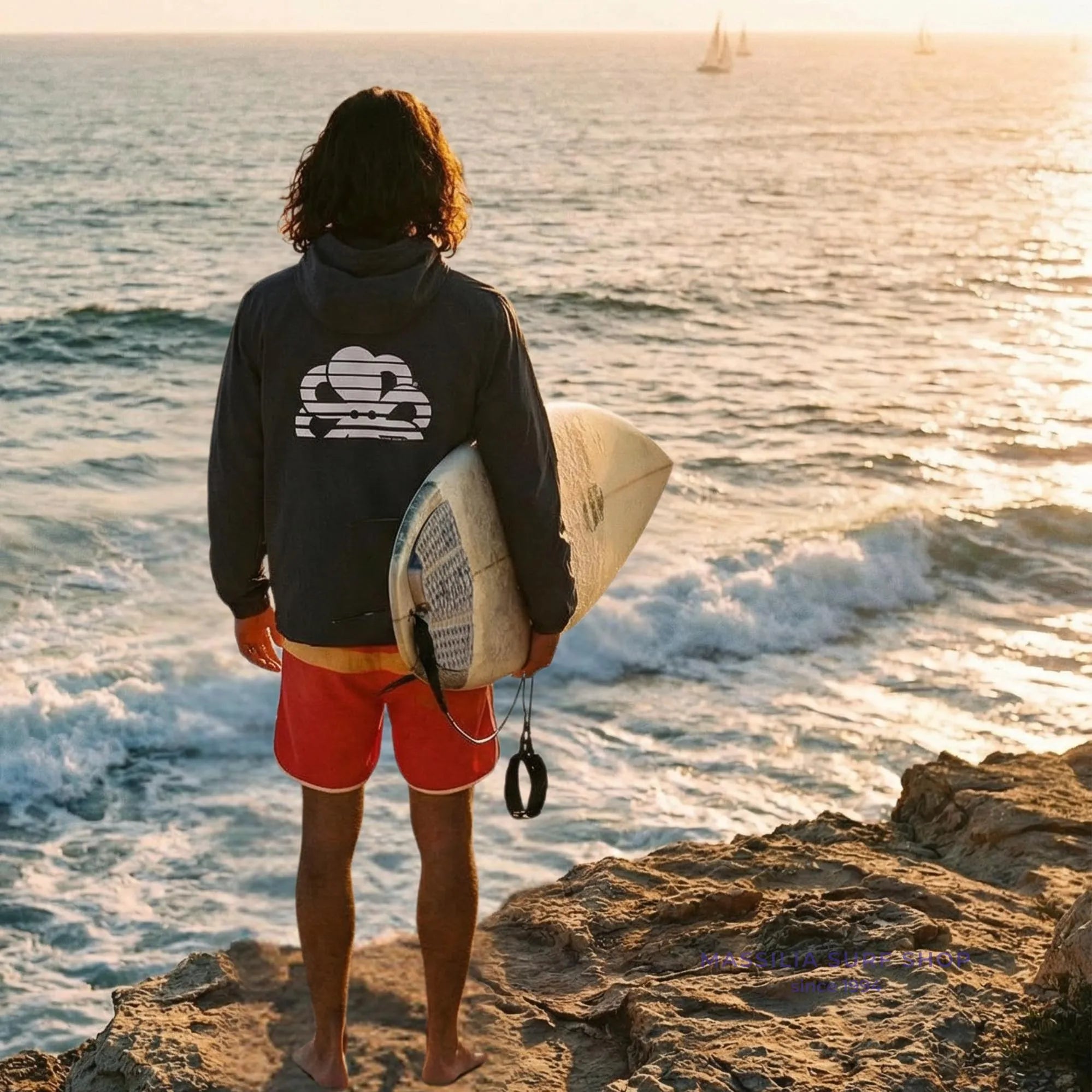 coupe vent noir avec logo poulpe dans le dos porte par un homme lifestyle surf