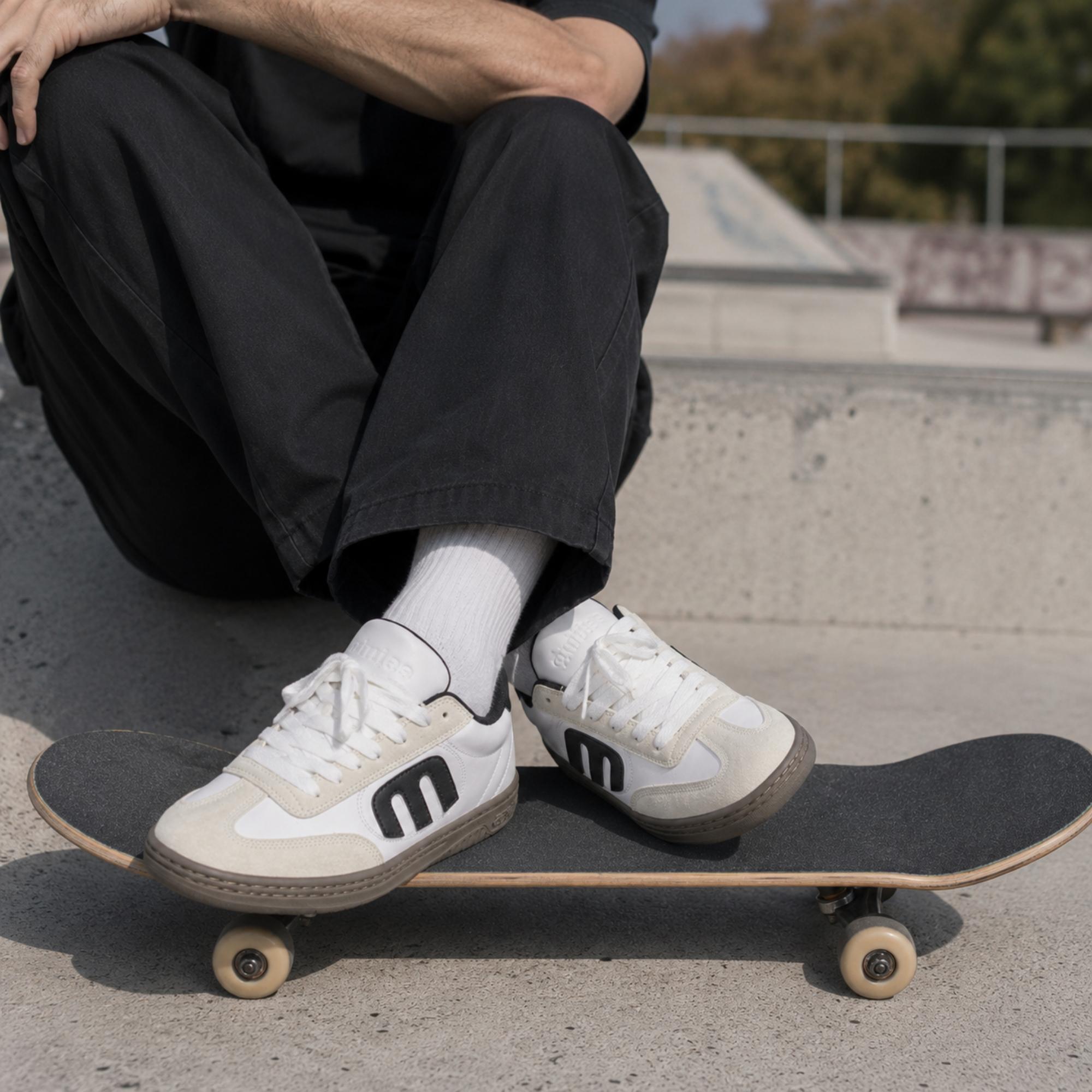 Chaussures Etnies Locut white black gum portées sur un skateboard