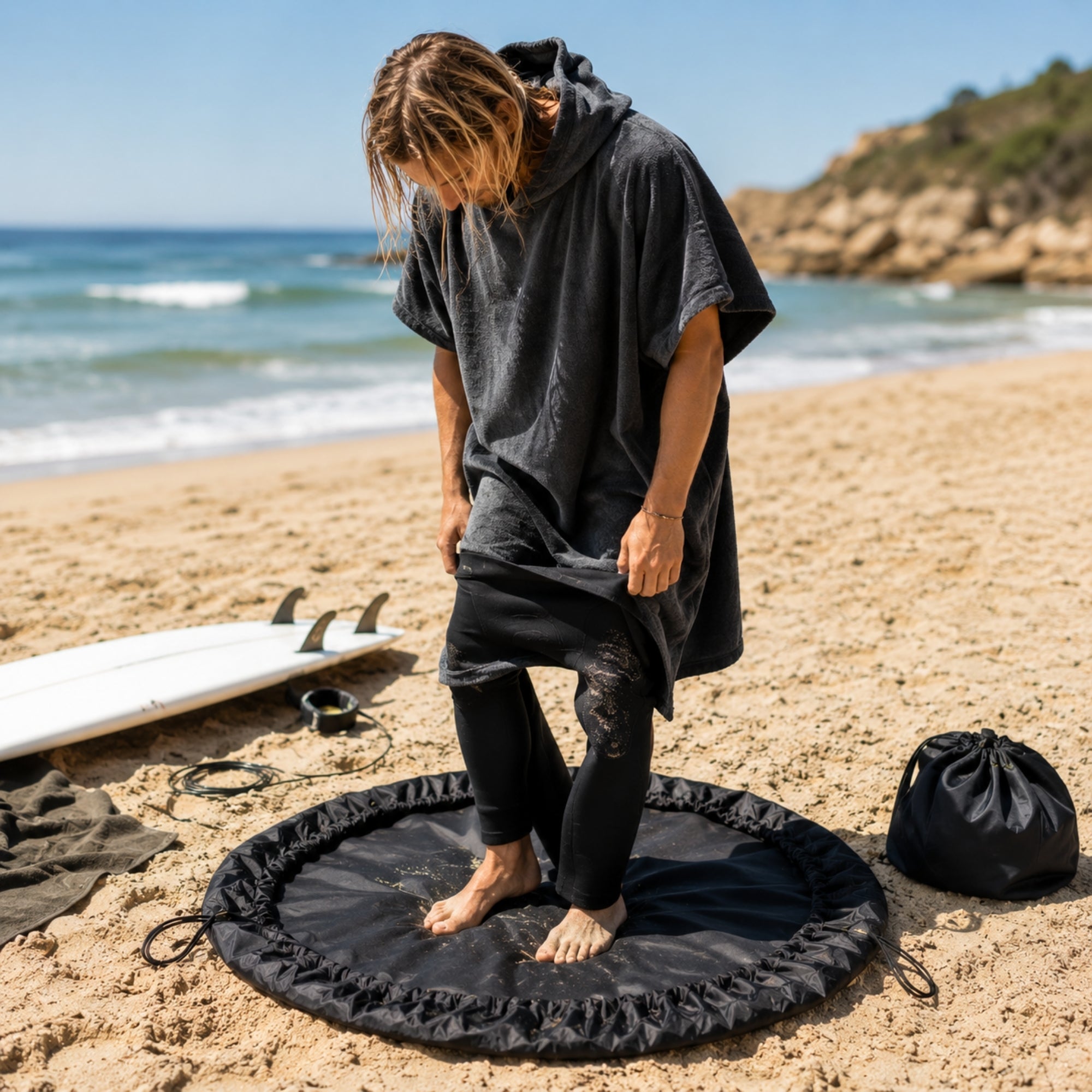homme en poncho enlevant sa combinaison sur change mat fcs arrier plan plage