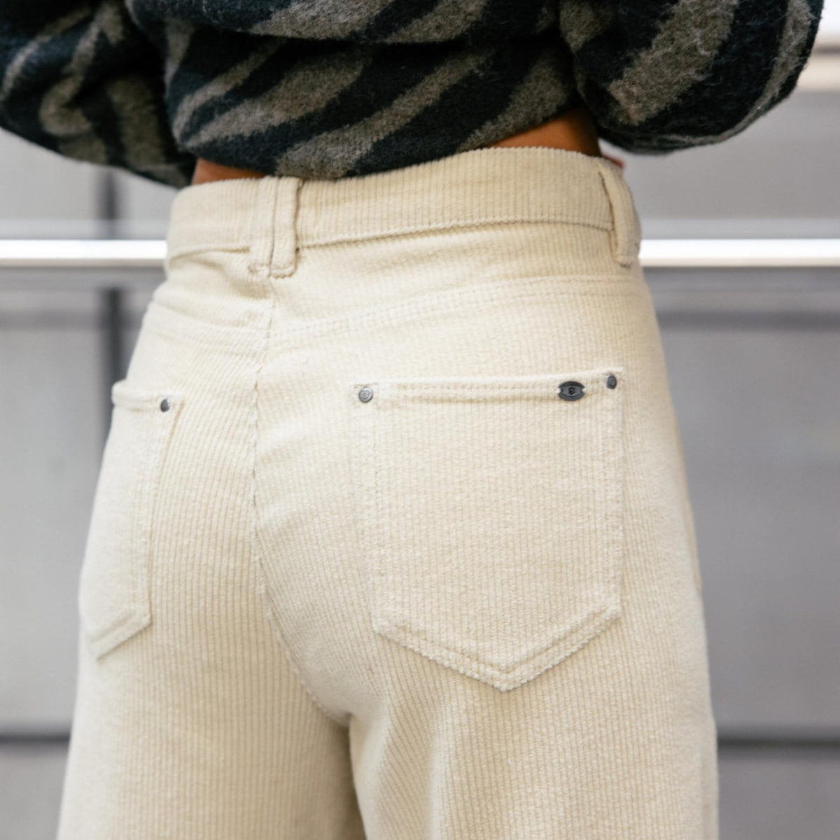 Vue arrière rapprochée du pantalon beige crème avec deux poches plaquées et coutures apparentes.