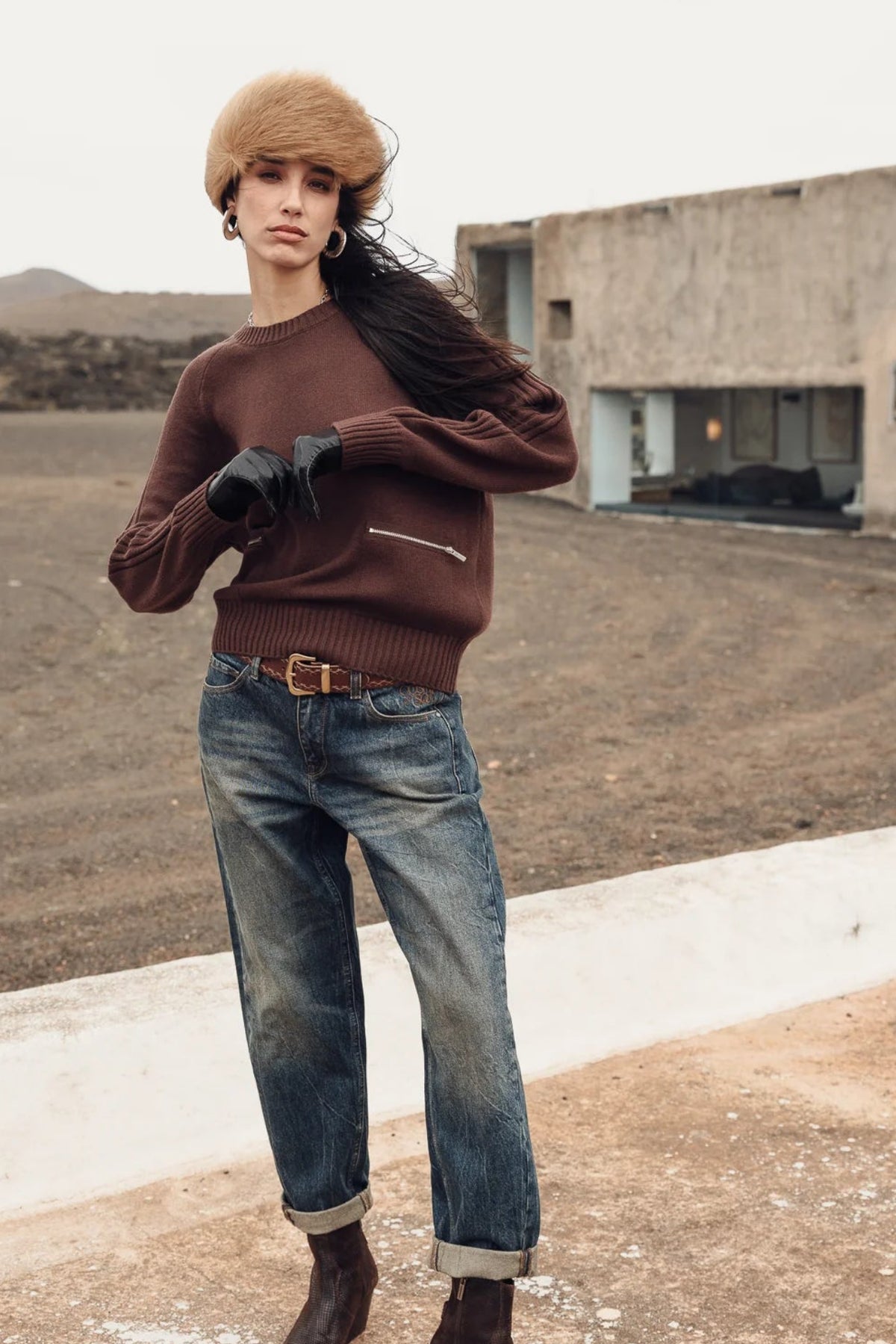 femme en extérieur debout avec pull marron pelson chocolate, jans large délavé, bottines noires et chapka en fourrure