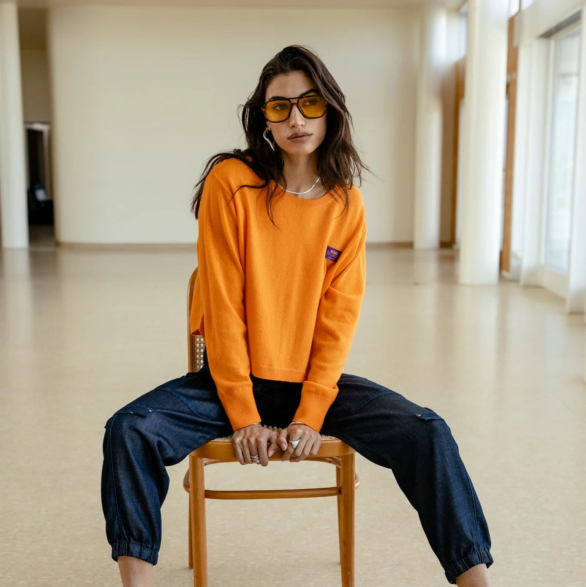 Pull court Freeman T. Porter Pharos Orange Peel porté assis, maille orange vive et silhouette ample aux épaules tombantes
