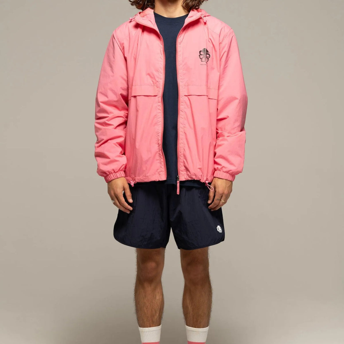 Silhouette complète en coupe-vent rose avec short marine, manches élastiquées et volume droit légèrement ample