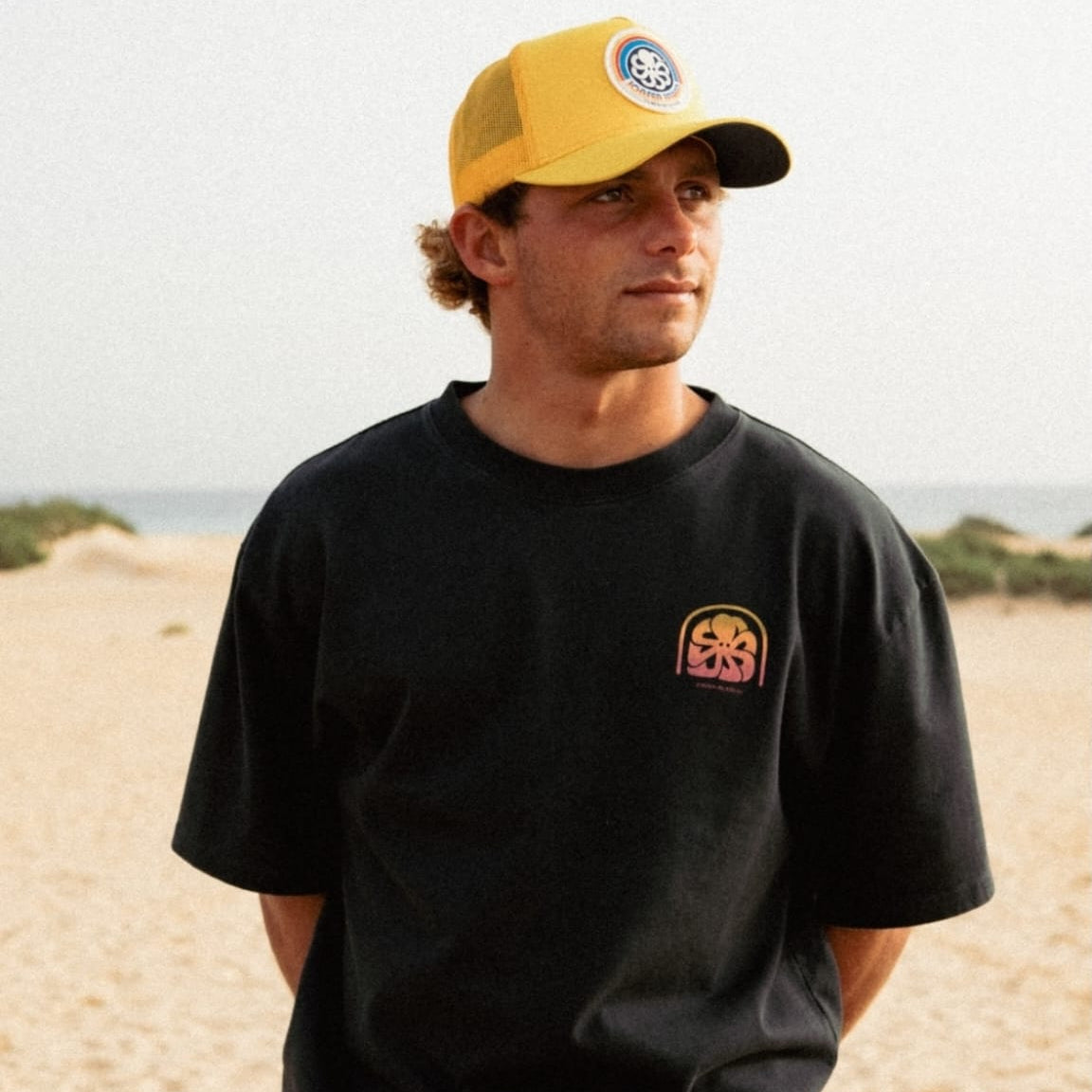 porté par jules agazar surfer vue de face t-shirt noir avec casquette jaune