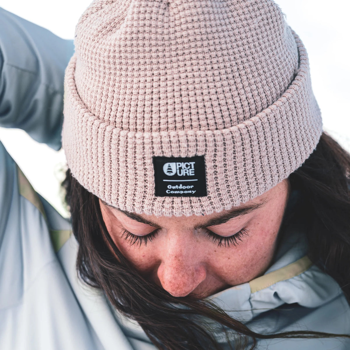 Bonnet Picture Organic Clothing York Beanie Pure Cashmere porté en gros plan, maille gaufrée beige clair et étiquette logo sur le revers