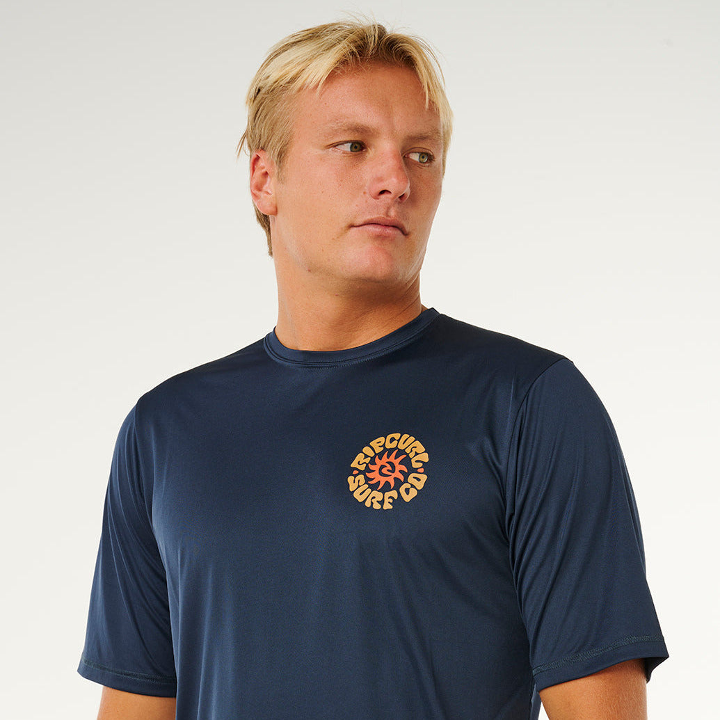 Tee-shirt lycra Rip Curl Pacific Rinse Navy porté, avec logo poitrine jaune et protection solaire 50 UPF