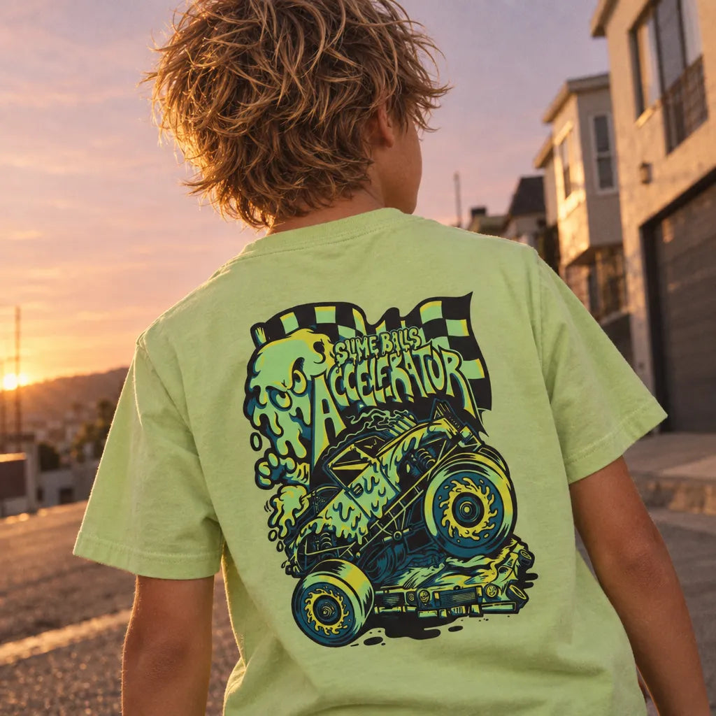 Enfant de dos portant le t-shirt Santa Cruz Youth Slime Balls Accelerator Green Glow avec grand graphisme voiture Slime Balls au skatepark au coucher du soleil