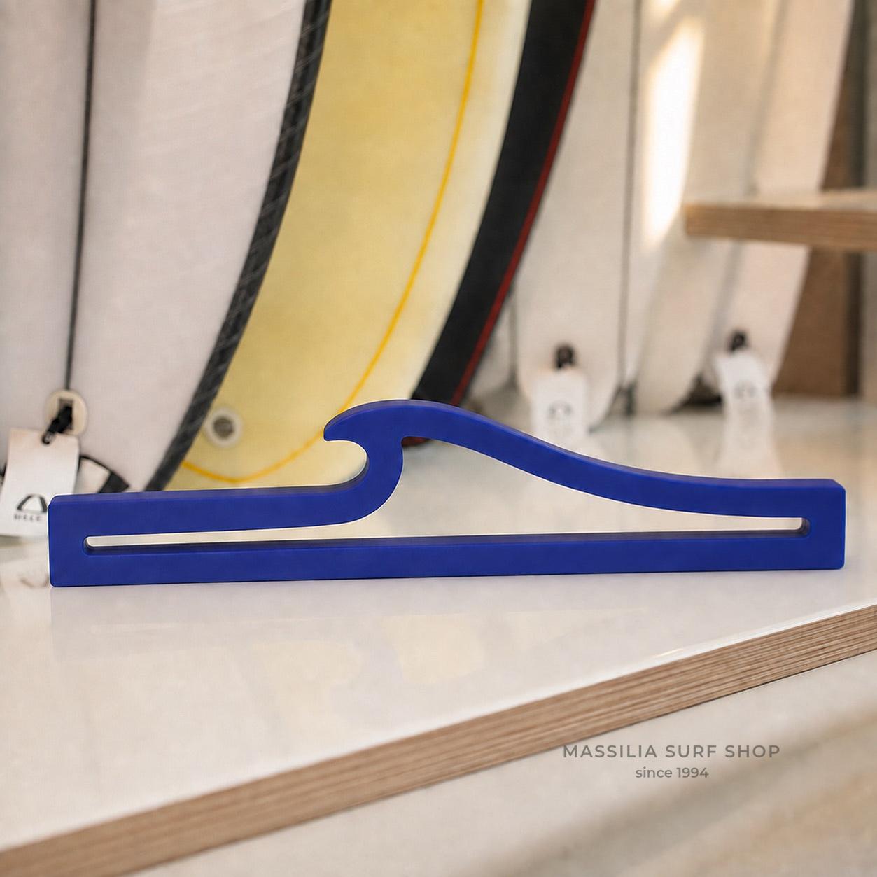Sculpture en forme de vague bleue présentée devant des planches de surf, dans boutique massilia surf shop