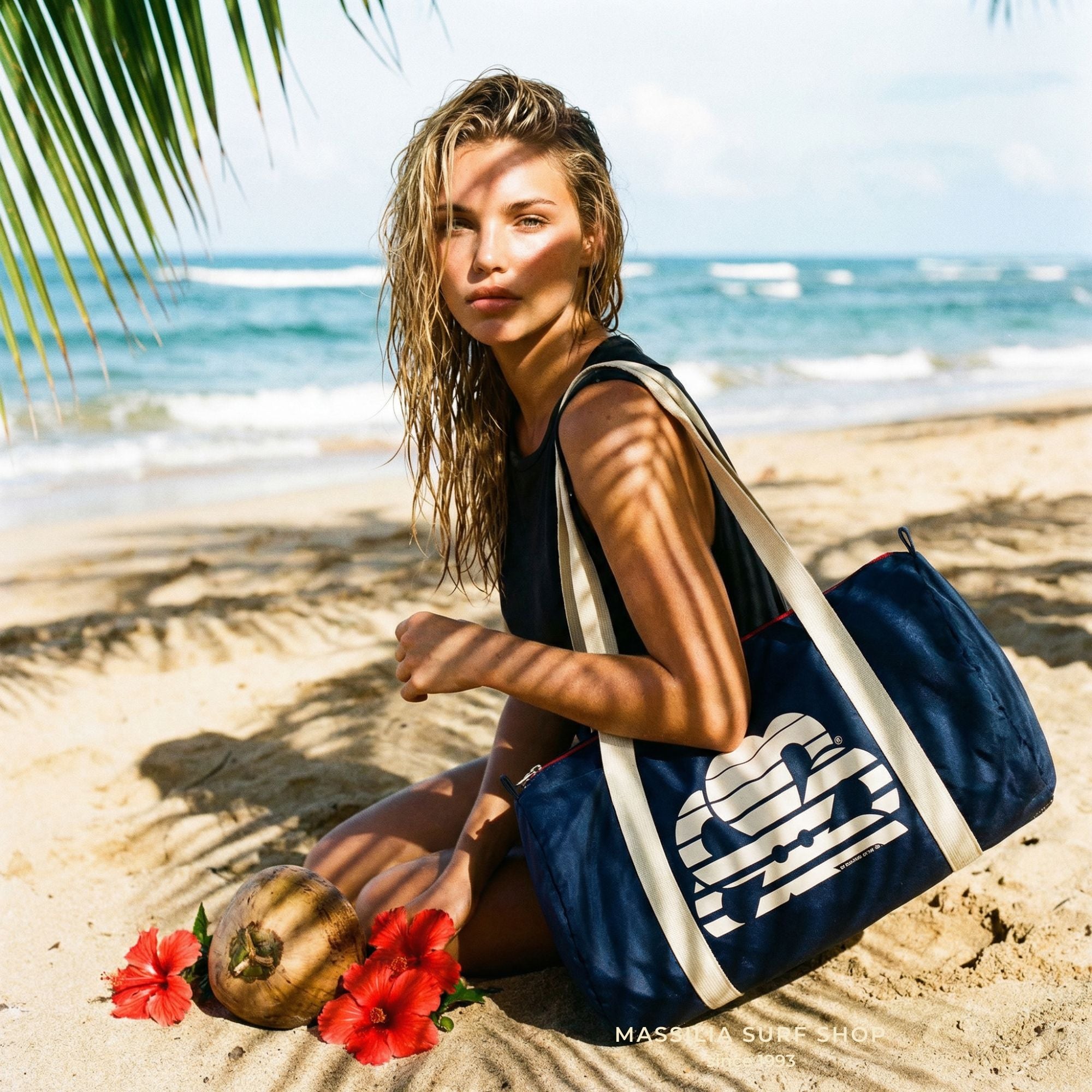 bowling bag navy jonsen island sur epaule d une femme assise sur la plage avec hibiscus