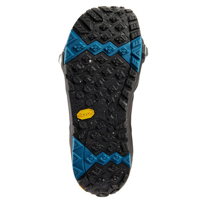 Semelle extérieure noire vue dessous, crampons profonds, zones d’adhérence bleues et insert Vibram jaune au centre