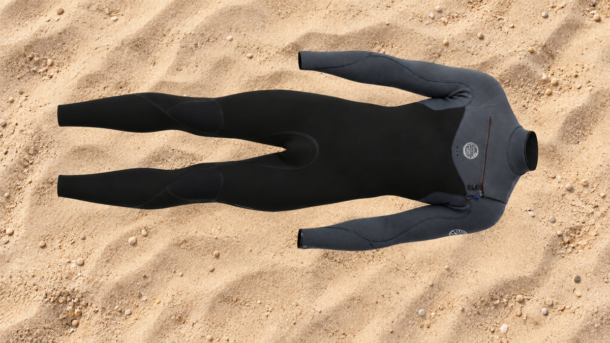 combinaison de surf homme noire et grise posée sur le sable  vue coté exterieur