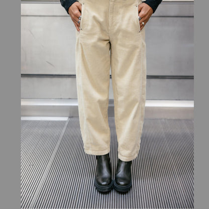 Pantalon Rosalia Veluto porté de face avec les mains dans les poches, jambes légèrement fuselées et chaussures noires.