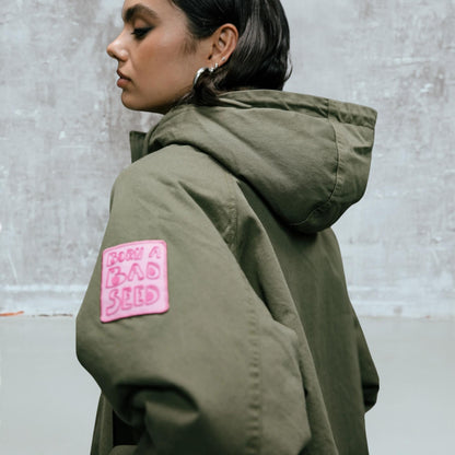 Détail du haut de manche du Vendana Leo Olive Night avec écusson rose brodé sur coton vert olive