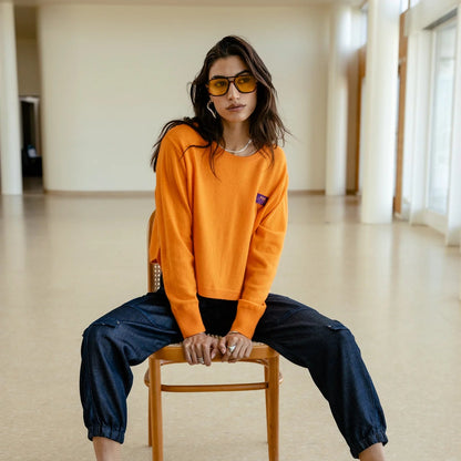 Pull court Freeman T. Porter Pharos Orange Peel porté assis, maille orange vive et silhouette ample aux épaules tombantes