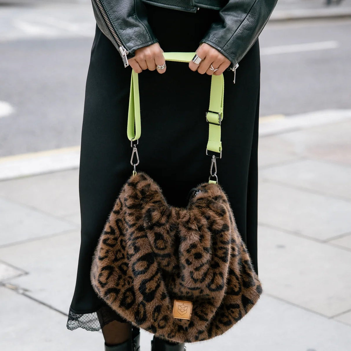 Sac fourrure léopard porté par sa sangle, silhouette souple et détails vert fluorescent contrastants