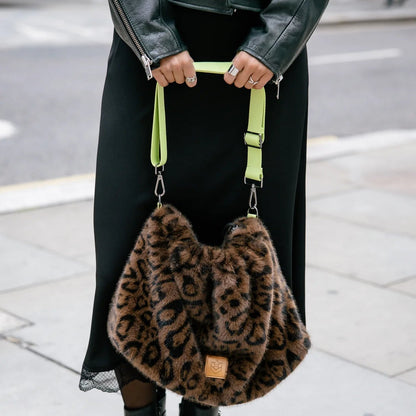 Sac fourrure léopard porté par sa sangle, silhouette souple et détails vert fluorescent contrastants