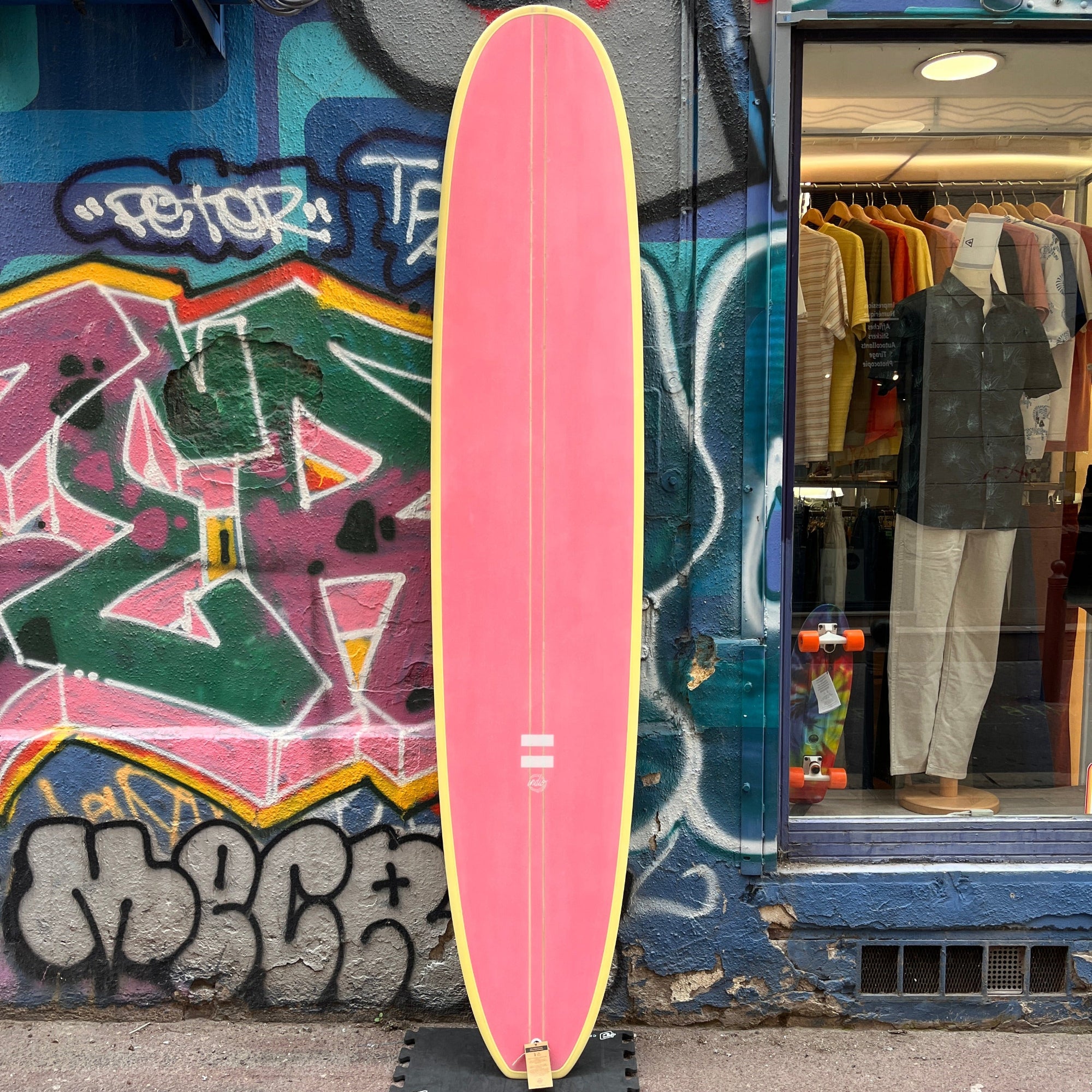 longboard indio rose et jaune pose devant la facade du magasin massilia surf shop
