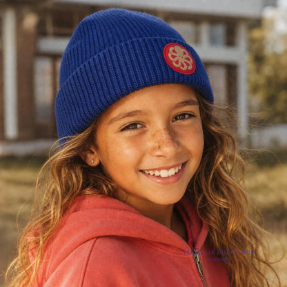 Bonnet surfwear unisexe Jonsen Island Laine bleu porté par une fille, maille côtelée et écusson rond à pieuvre corail