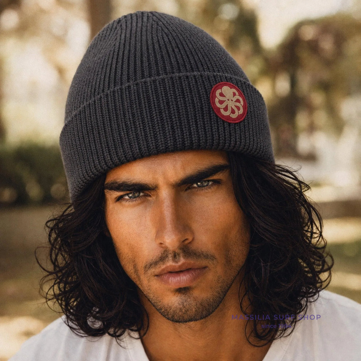 Accessoire surfwear Jonsen Island gris anthracite porté par un homme, maille côtelée et médaillon pieuvre rouge sur le revers