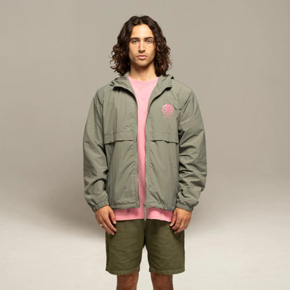 Windbreaker kaki porté de face en studio, coupe droite zippée avec t-shirt rose visible sous la veste