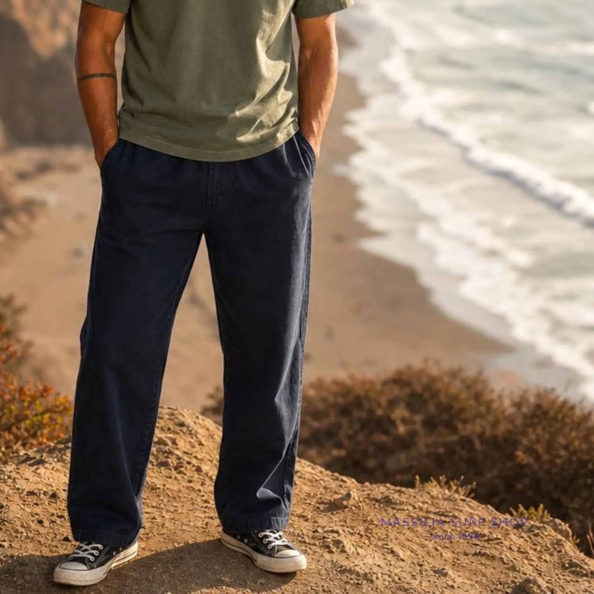 Reyes bleu marine porté par un homme en bord de mer, jambe large et tombé souple avec poches latérales discrètes