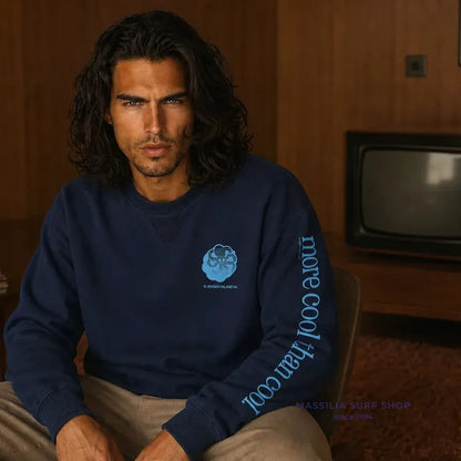 Sweat surfwear Jonsen Island bleu marine porté assis, coupe droite à col rond et inscription turquoise courant sur la manche