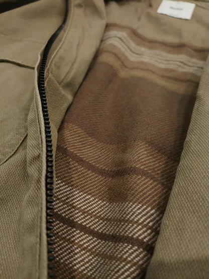 Gros plan sur l'intérieur de la veste Katin Petrol Jacket, doublure en flanelle à carreaux bruns et beiges et fermeture éclair noire.