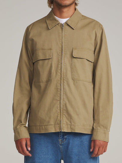 Veste workwear Katin Elmwood portée de face avec jean bleu, deux poches poitrine à rabat et fermeture centrale zippée.