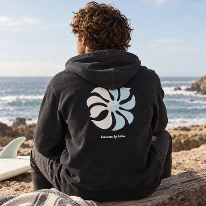 sweat noir homme katin porté assis sur une plage vue de dos avec motif blanc et bleu ciel