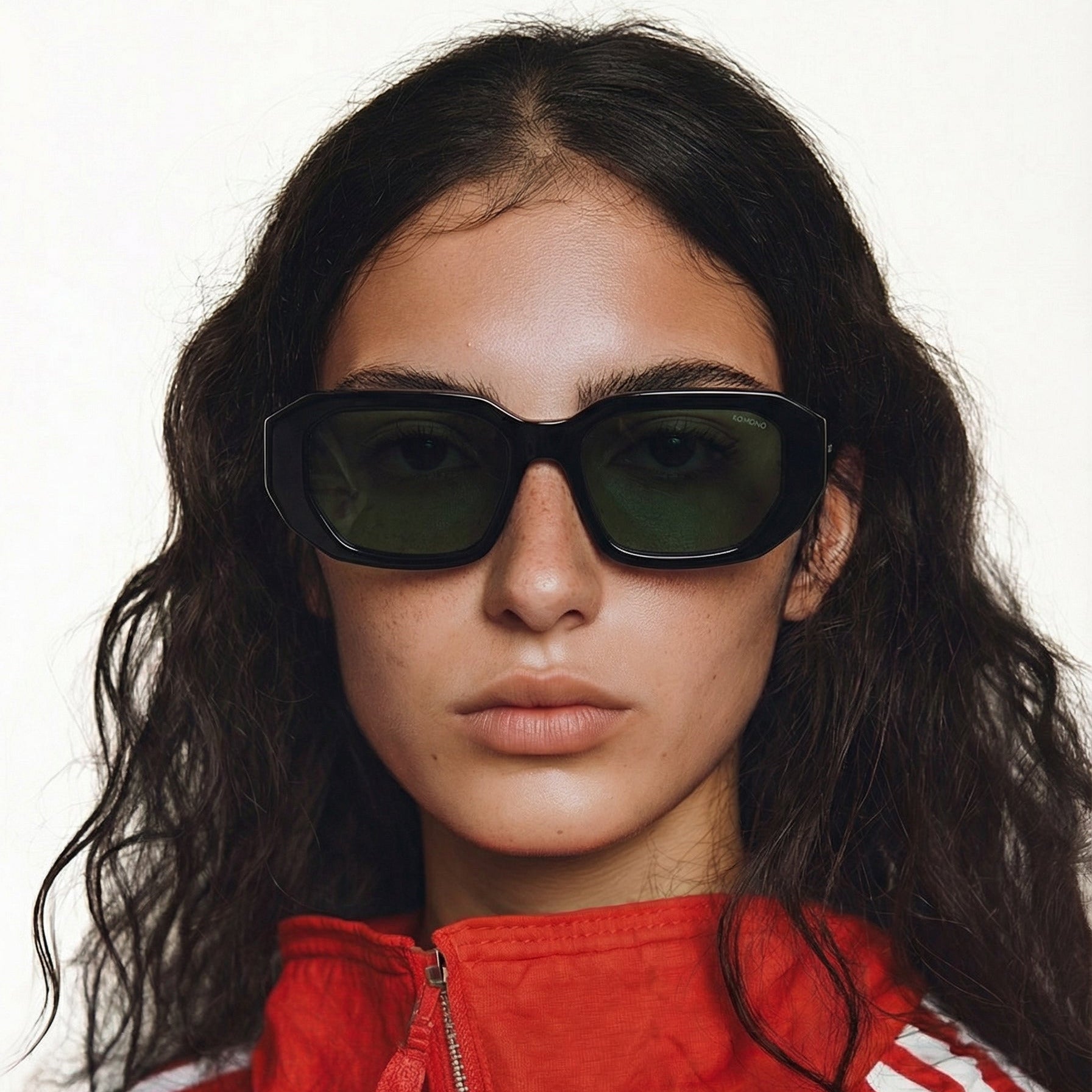 femme brune avec lunettes noires rectangulaire et veste de sport rouge