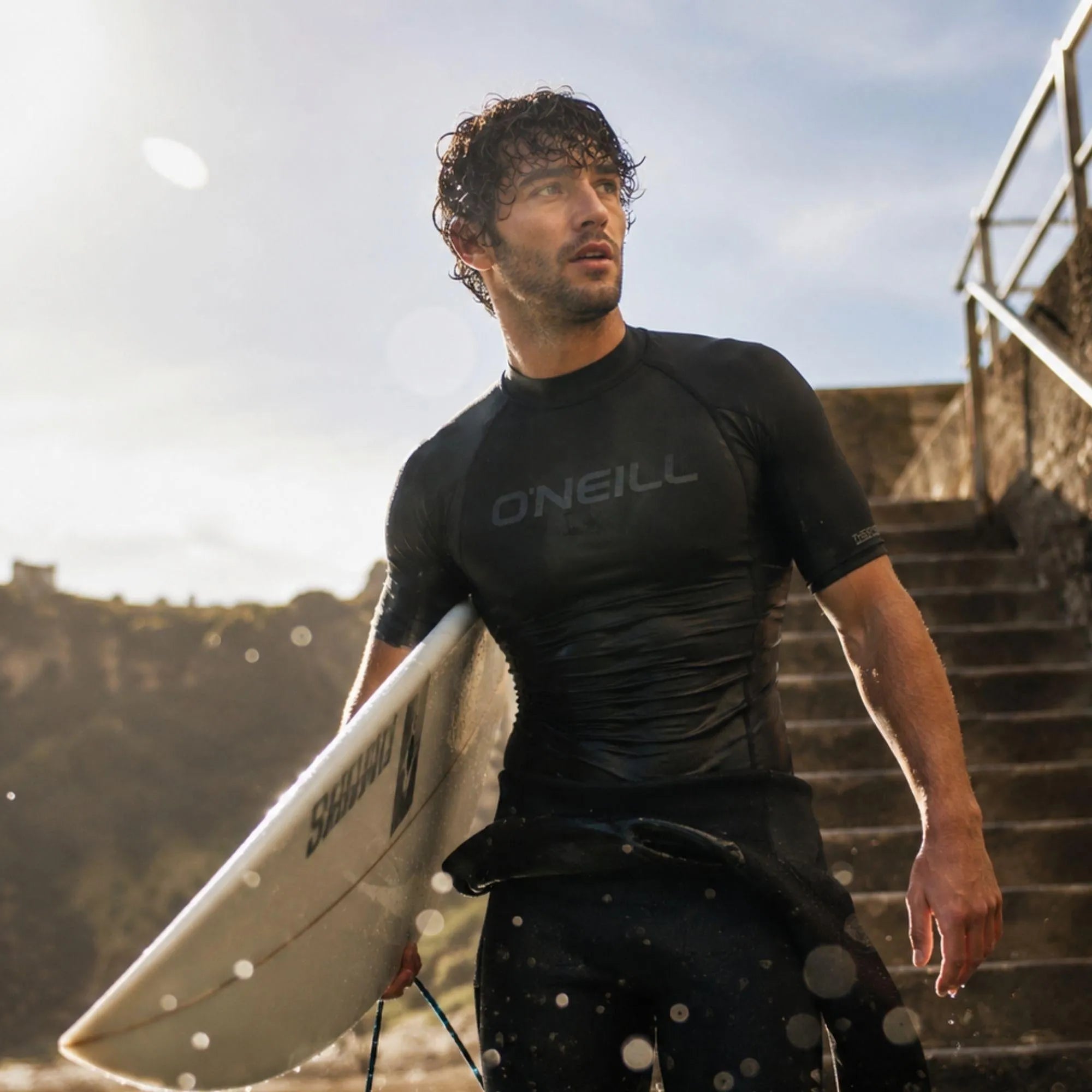 Top thermique O’Neill Black manches courtes porté au bord de l’eau après le surf
