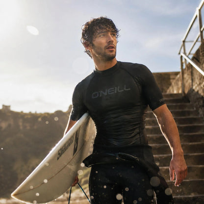 Top thermique O’Neill Black manches courtes porté au bord de l’eau après le surf