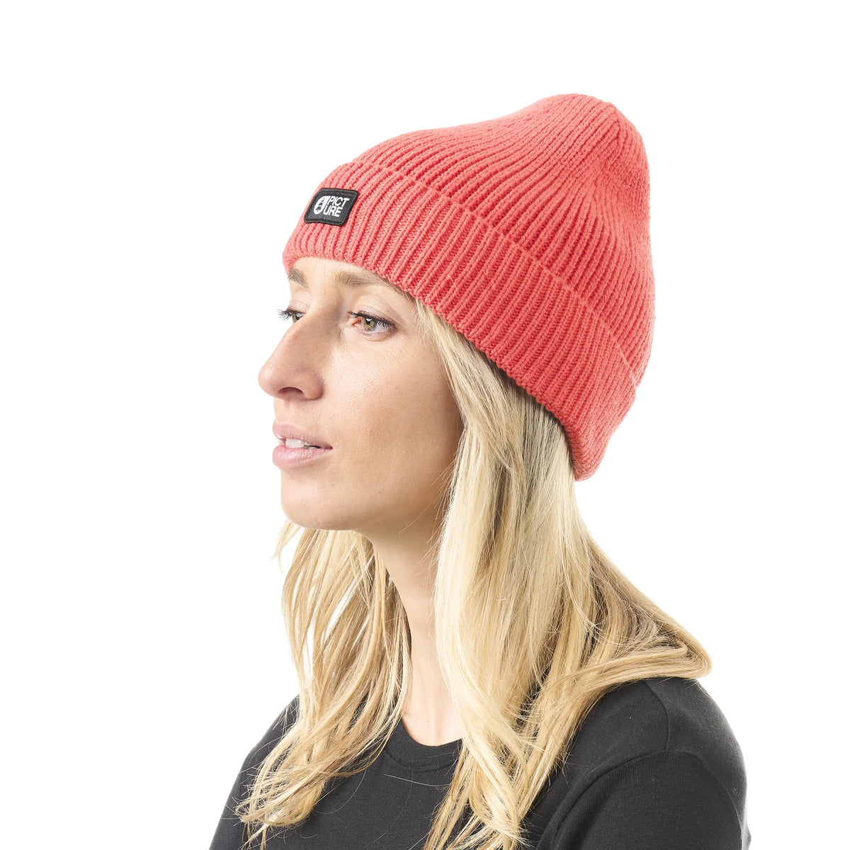Bonnet unisexe Picture Organic Clothing Colino Beanie Living Coral porté de profil, maille côtelée corail et étiquette logo sur le revers