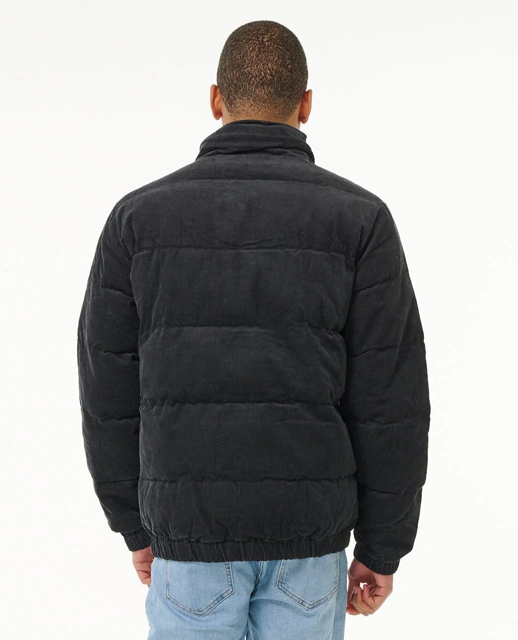 Porté de dos, le blouson en velours côtelé révèle une coupe décontractée et de larges panneaux matelassés