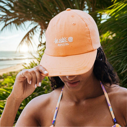 casquette orange portee par une femme background plage et foret
