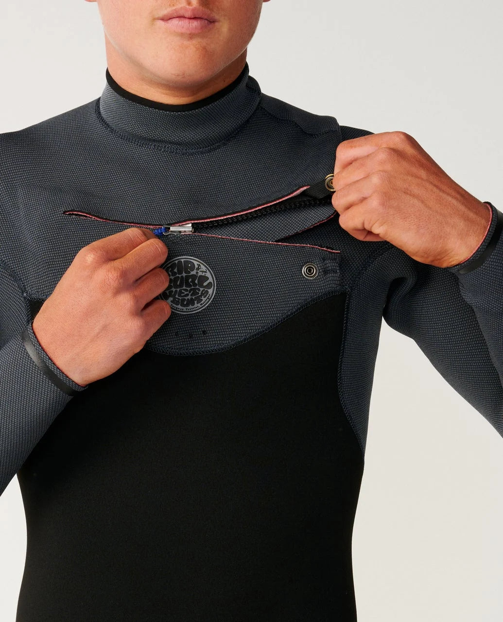 Gros plan sur l’ouverture Chest Zip et le panneau poitrine, avec fermeture horizontale et emblème circulaire