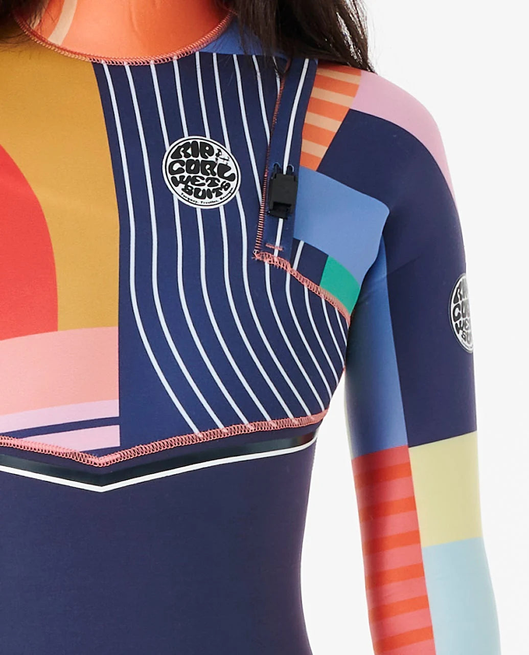 Gros plan du buste, avec rayures verticales bleu et blanc, blocs colorés géométriques et petit emblème Rip Curl sur la poitrine