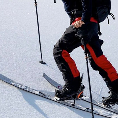homme en action montant une pente enneigée avec splitboard séparé en 2