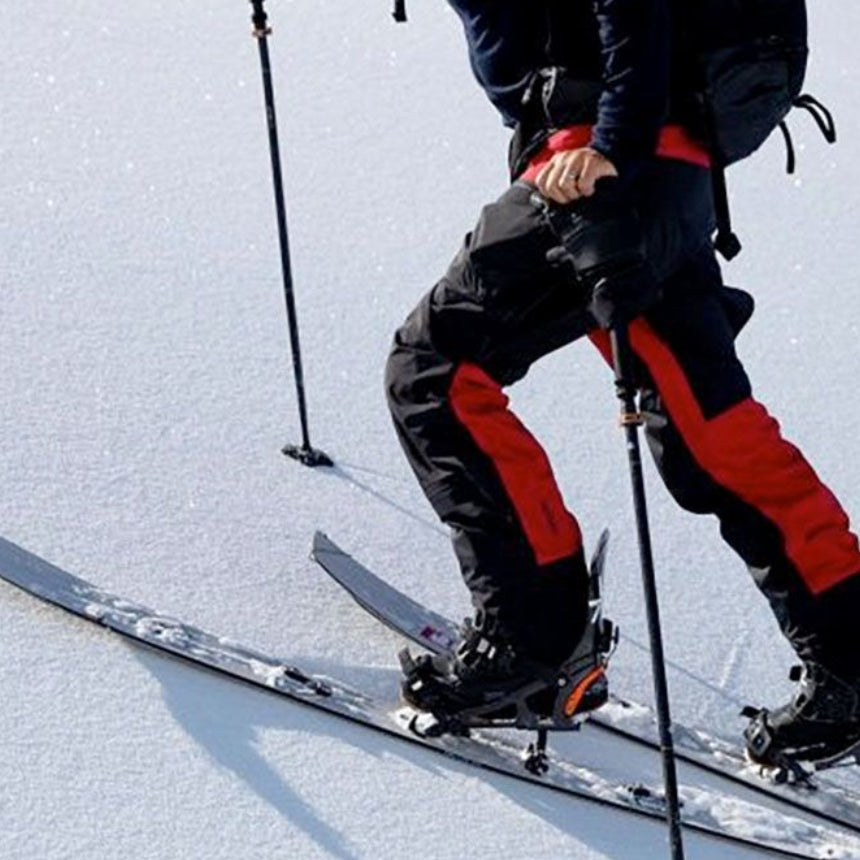 homme en action montant une pente enneigée avec splitboard séparé en 2