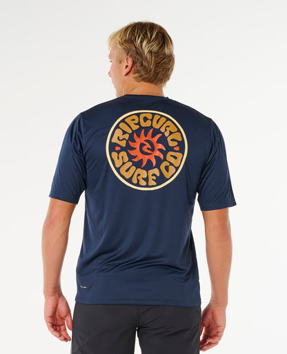 Tee-shirt lycra Rip Curl Pacific Rinse Navy porté en silhouette complète, coupe non moulante pour les sessions au soleil