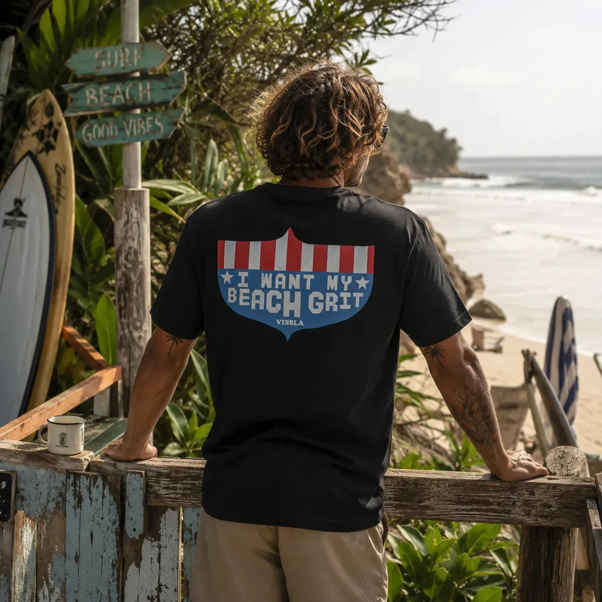 Tee-shirt homme Vissla noir I Want My Beach Grit porté de dos face à la plage, visuel surf vintage, ambiance surfwear premium
